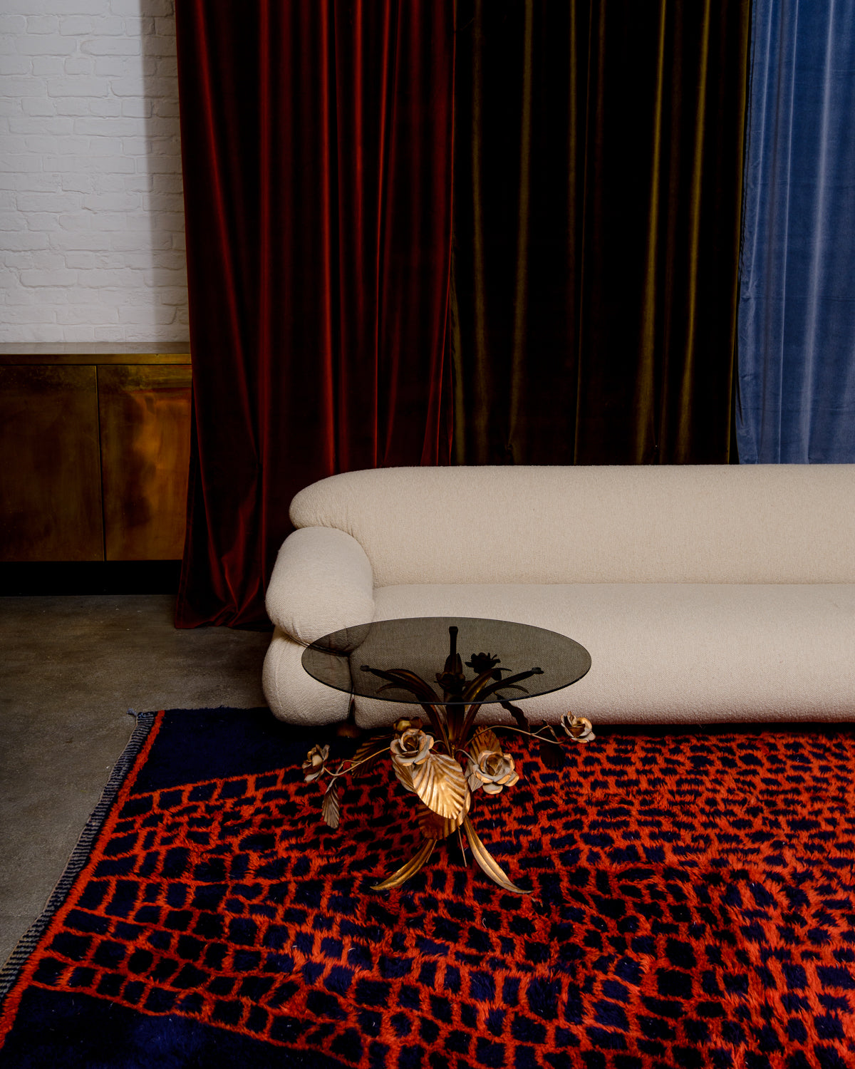 Berberlin Beni M'rirt rug in deep navy blue with contrasting rust red pattern, with velvet curtains, cream couch and art nouveau coffee table with ornate gold flowers and glass top.